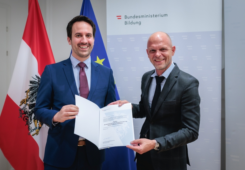 Bundesminister Christoph Wiederkehr überreicht das Dekret an IQS-Direktor Robert Klinglmair