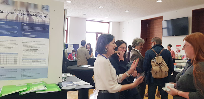 Eine Mitarbeiterin des IQS begrüßt Gäste am Informationsstand